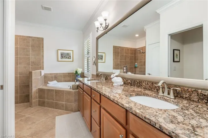 Bathroom with a walk in shower, a garden tub, light tile patterned floors, double vanity, and ornamental molding