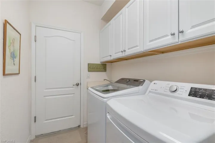 Washroom with independent washer and dryer, cabinet space, and light tile patterned floors