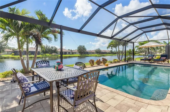 Swimming pool with a lanai, a water view, a sunroom, and a patio