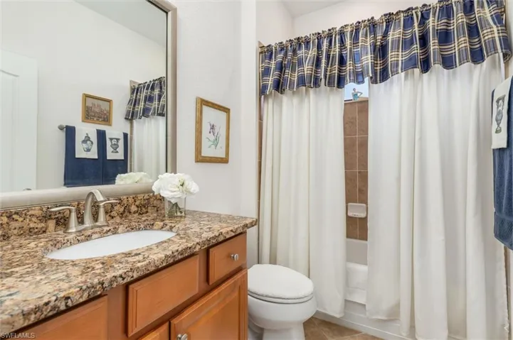 Full bathroom with shower / bath combo with shower curtain, vanity, and light tile patterned floors