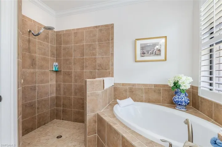 Full bath featuring a garden tub, a shower stall, and ornamental molding