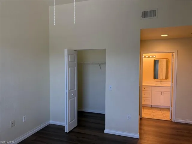 Unfurnished bedroom with dark wood-style flooring and connected bathroom