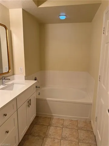 Bathroom with vanity, a garden tub, a textured ceiling, and light tile patterned flooring
