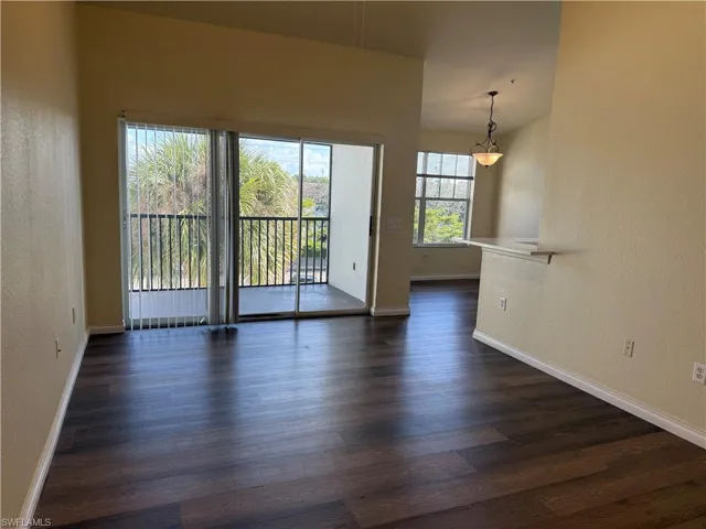 Spare room with a textured wall and dark wood-style flooring