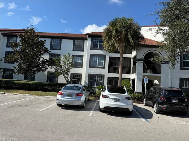 View of apartment building / complex featuring uncovered parking
