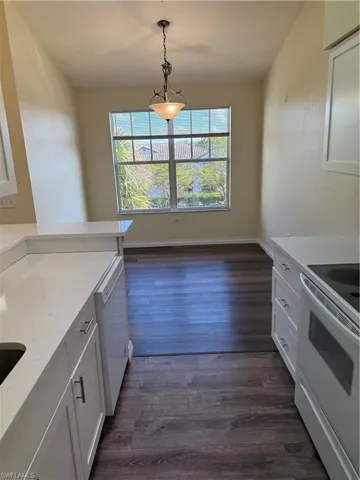 Kitchen featuring range, white cabinets, light stone counters, and hanging light fixtures
