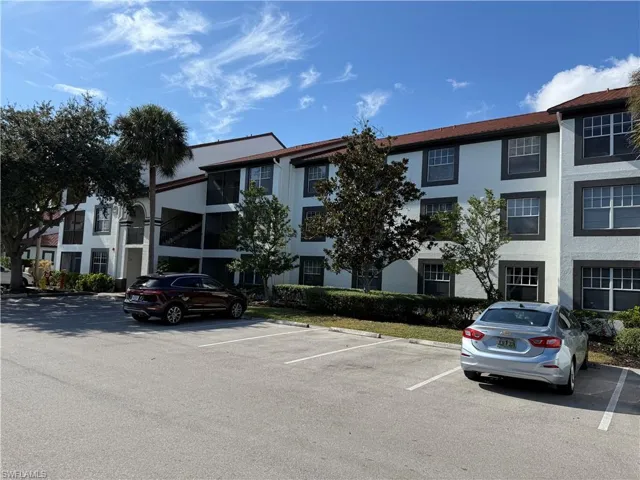View of apartment building / complex featuring uncovered parking