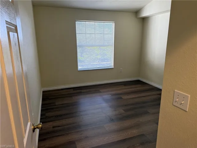 Spare room with a textured wall and dark wood-style floors