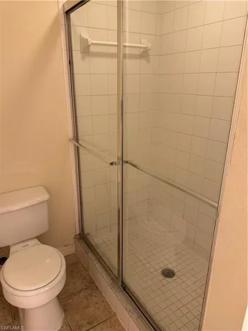 Bathroom with a stall shower, a textured wall, and light tile patterned floors