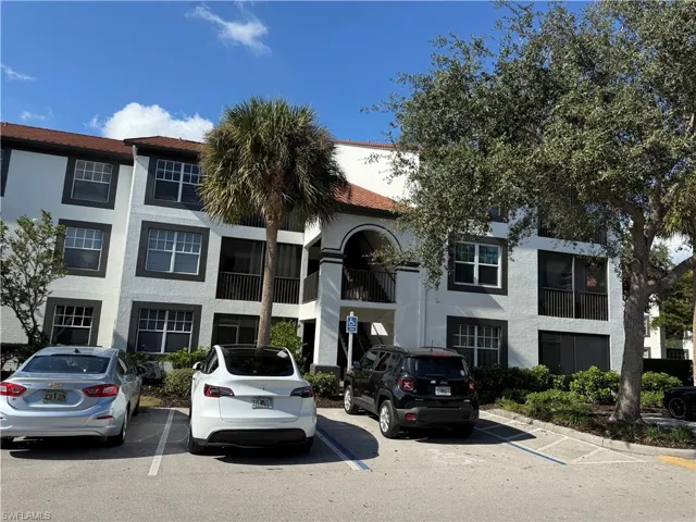View of apartment building / complex featuring uncovered parking