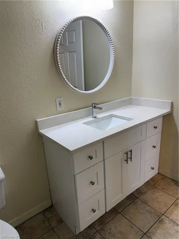 Half bath with a textured wall, vanity, and light tile patterned flooring