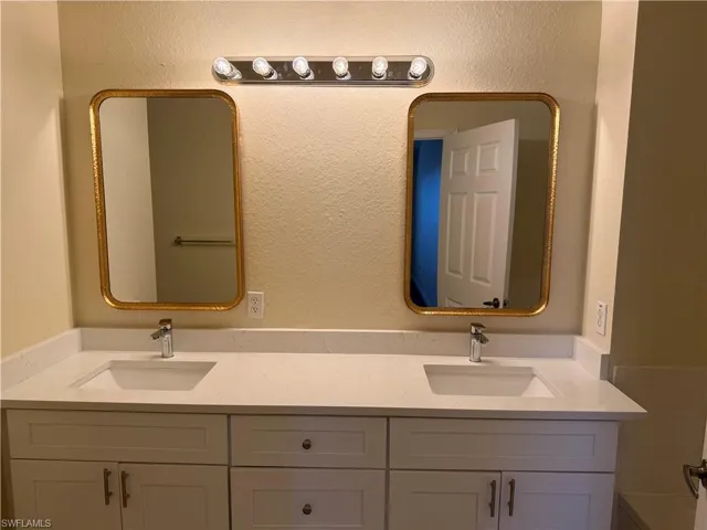 Full bathroom with double vanity and a textured wall
