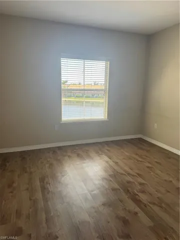 Room featuring wood-finish flooring and a window with horizontal blinds providing water exposure