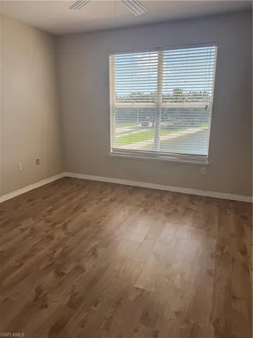 Room featuring wood-finish flooring, neutral wall paint, and a multi-pane window with horizontal blinds