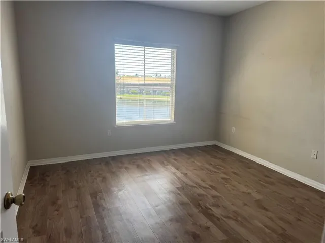 Interior space featuring wood-finish flooring, neutral wall tones, and a single window with horizontal blinds
