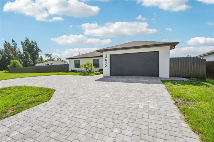 View of front of home with curved driveway, stucco siding, and an attached garage