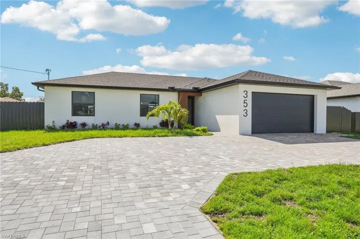 View of front facade with an attached garage, stucco siding, and decorative driveway