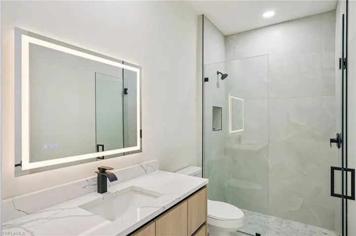 Full bath featuring vanity and a marble finish shower