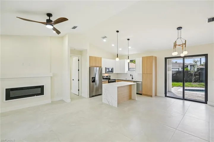 Kitchen featuring decorative light fixtures, appliances with stainless steel finishes, modern cabinets, lofted ceiling, and open floor plan