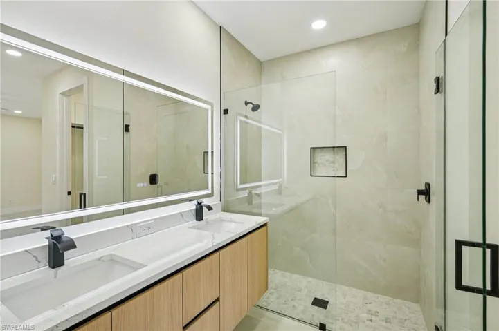 Full bath featuring a stall shower, double vanity, and recessed lighting