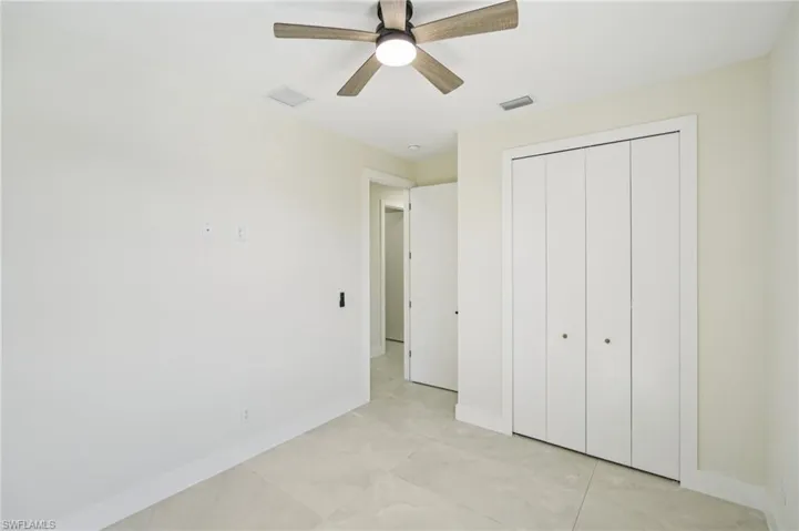 Unfurnished bedroom featuring ceiling fan, light tile patterned floors, and a closet