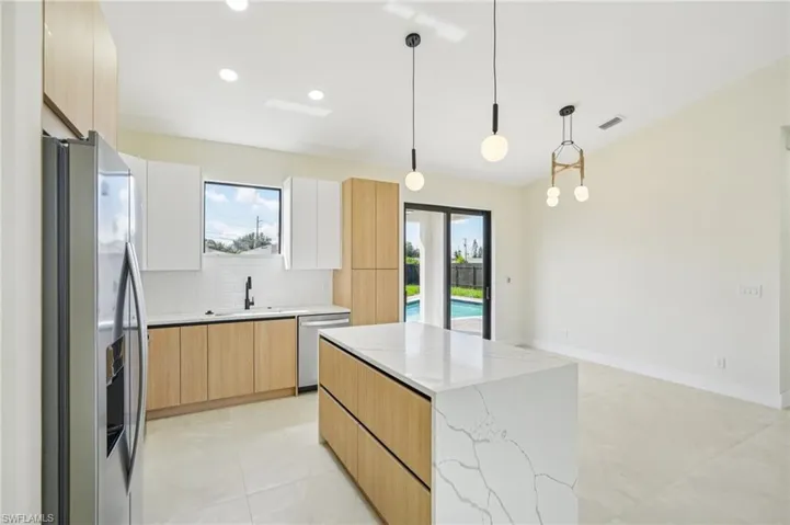 Kitchen featuring light brown cabinets, appliances with stainless steel finishes, tasteful backsplash, a center island, and recessed lighting