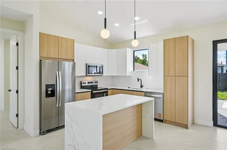 Kitchen featuring appliances with stainless steel finishes, pendant lighting, decorative backsplash, modern cabinets, and a kitchen island