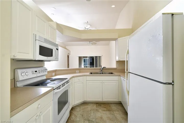 Kitchen featuring white appliances, white cabinetry, and light countertops