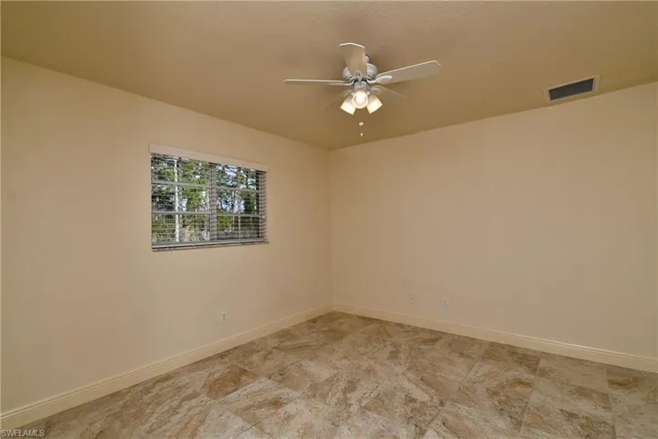 Unfurnished room featuring a ceiling fan and baseboards