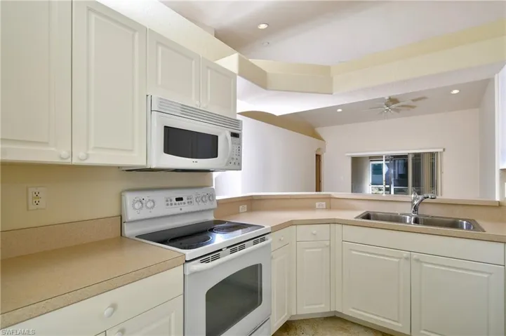 Kitchen featuring white appliances, light countertops, white cabinetry, a ceiling fan, and recessed lighting