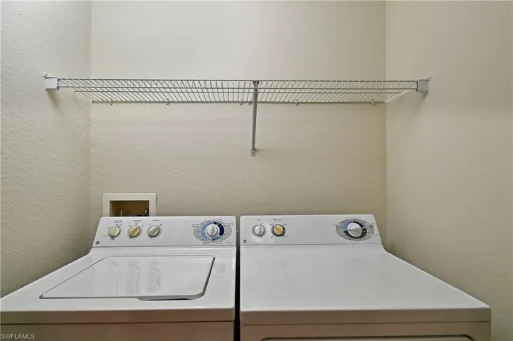 Laundry area with a textured wall and independent washer and dryer