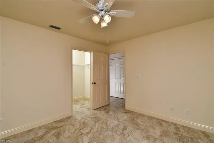 Unfurnished bedroom with a spacious closet and a ceiling fan