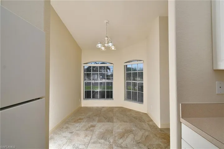 Unfurnished dining area with suspended lighting, a textured wall, and lofted ceiling