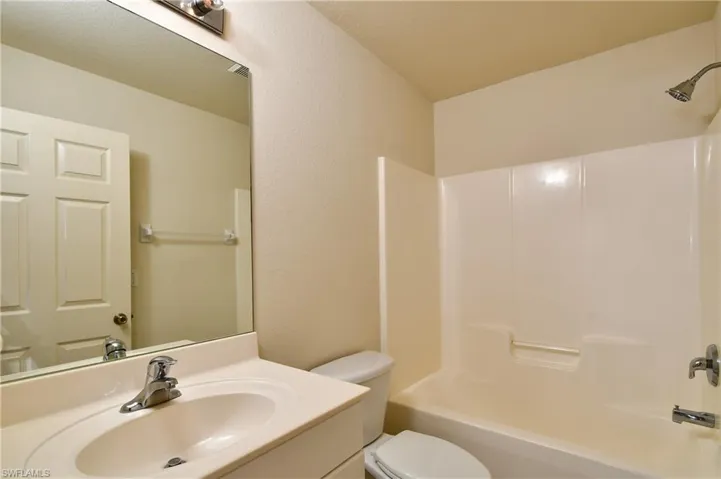 Bathroom featuring vanity, shower / washtub combination, and a textured wall