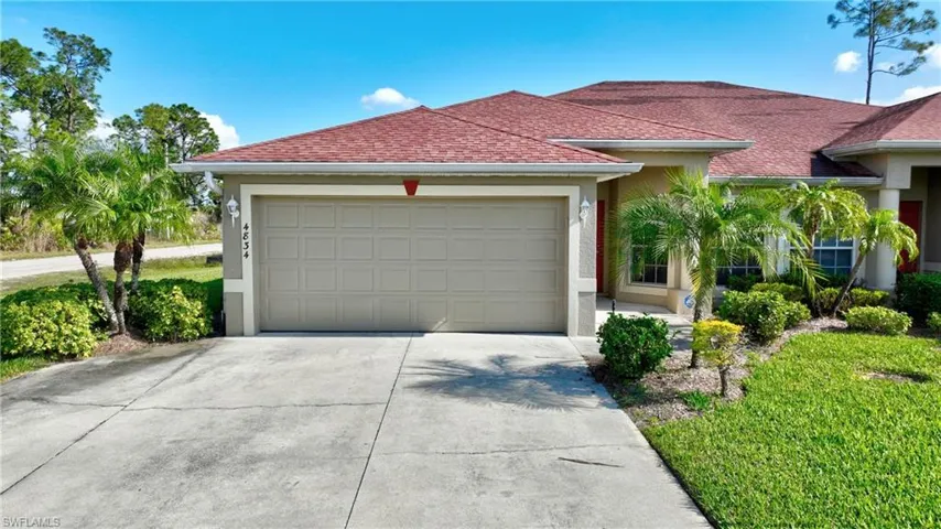 View of front of home featuring an attached garage, concrete driveway, stucco siding, and a shingled roof