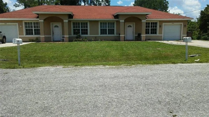 Duplex property featuring a red tile roof, stucco exterior, multiple front-facing windows, and attached garages