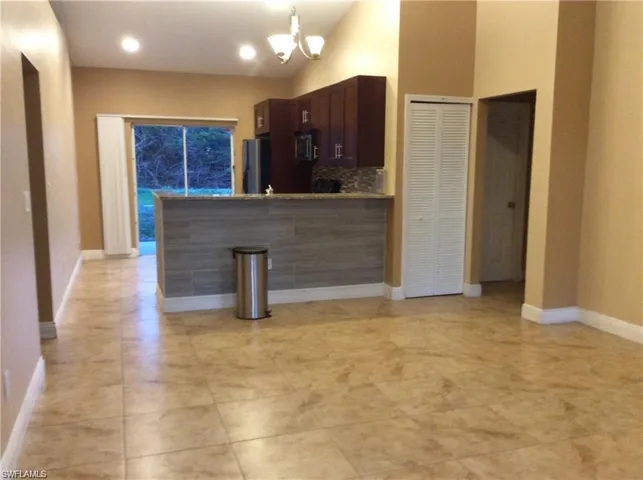 Open-concept living space with tile flooring throughout, vaulted ceiling, recessed lighting, and sliding glass door access to the exterior