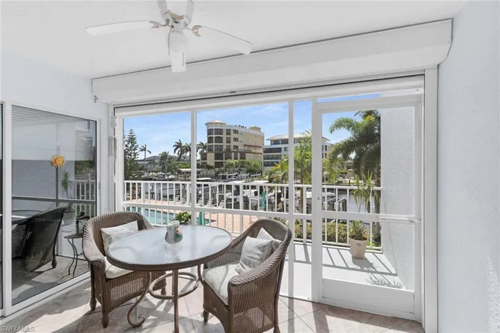 Sunroom / solarium with ceiling fan, tile patterned floors, and a water view