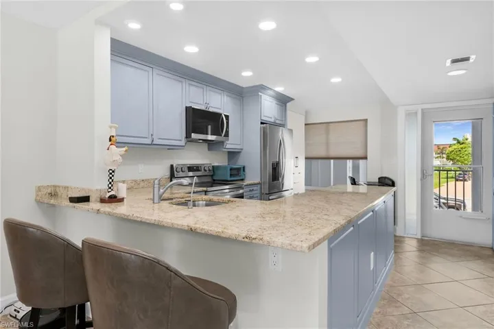 Kitchen with stainless steel appliances, a peninsula, recessed lighting, a breakfast bar area, and light tile patterned floors