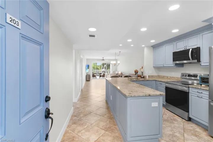 Kitchen featuring electric range, recessed lighting, a peninsula, light tile patterned flooring, and light stone countertops