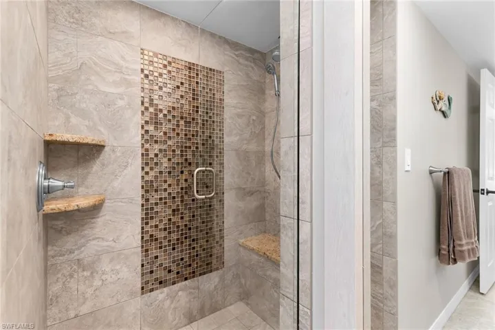 Full bathroom featuring a shower stall and baseboards