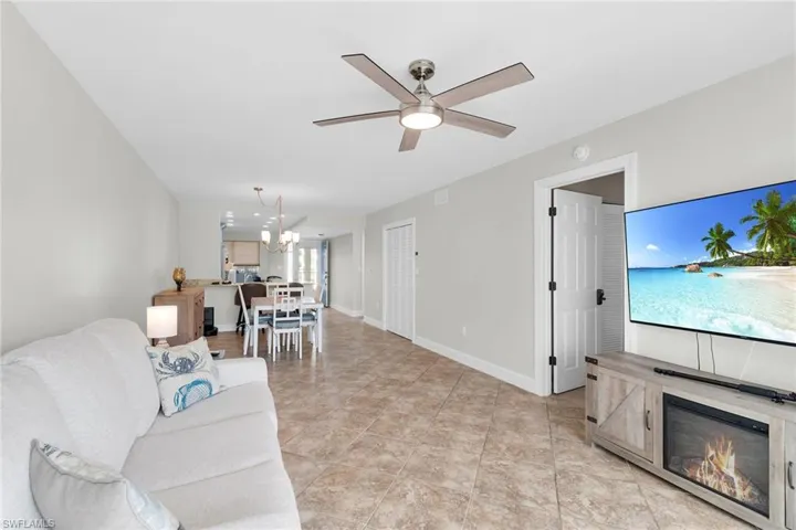 Living room featuring a chandelier, ceiling fan, and a glass covered fireplace