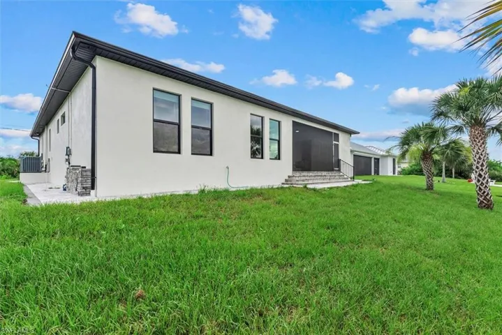 Rear view of house with a lawn and stucco siding