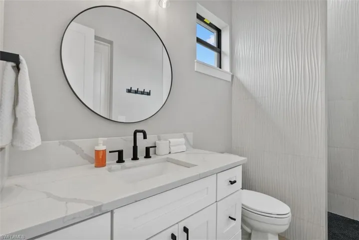 Full bath featuring vanity, a walk in shower, and tile walls