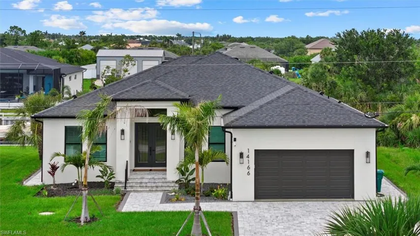 View of front of property with french doors, stucco siding, an attached garage, a front lawn, and decorative driveway