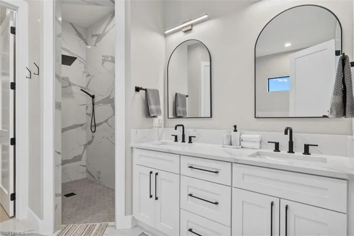 Full bath with double vanity, a marble finish shower, and recessed lighting
