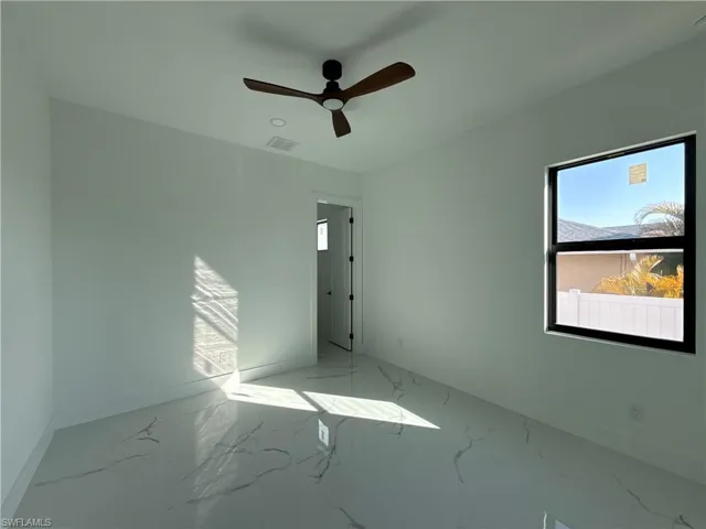 Empty room featuring plenty of natural light, ceiling fan, and marble finish flooring