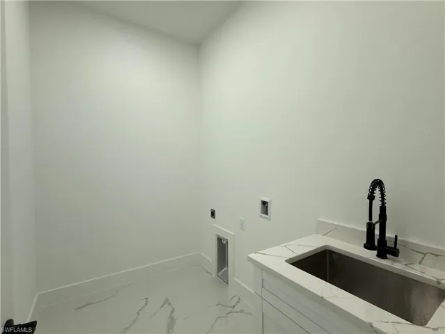Laundry room with hookup for a washing machine, hookup for an electric dryer, light marble finish flooring, and cabinet space