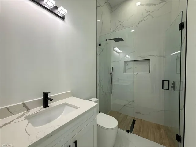 Full bathroom featuring vanity and a marble finish shower