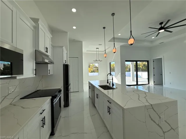 Kitchen featuring white cabinetry, electric range, light stone countertops, stainless steel microwave, and light marble finish flooring